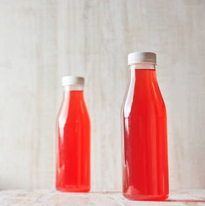 Bottled berry juice on a light, wooden background.