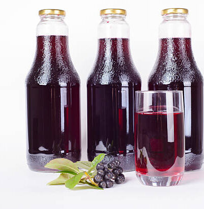 Three bottles of syrup made from aronia berries and glass