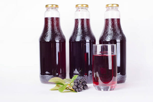 Three bottles of syrup made from aronia berries and glass