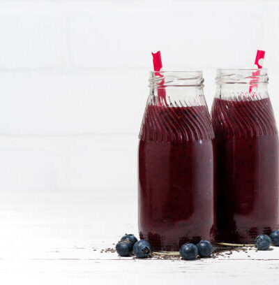 Healthy berry smoothie in jars on white background, horizontal